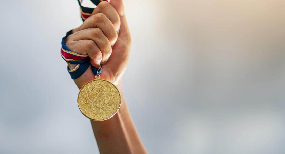 Raised hand holding a gold medal 
