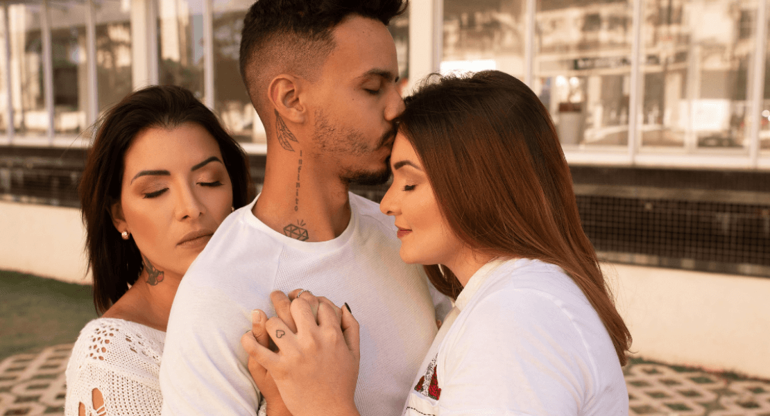 Trouple composé d'un homme et deux femmes qui s'enlacent