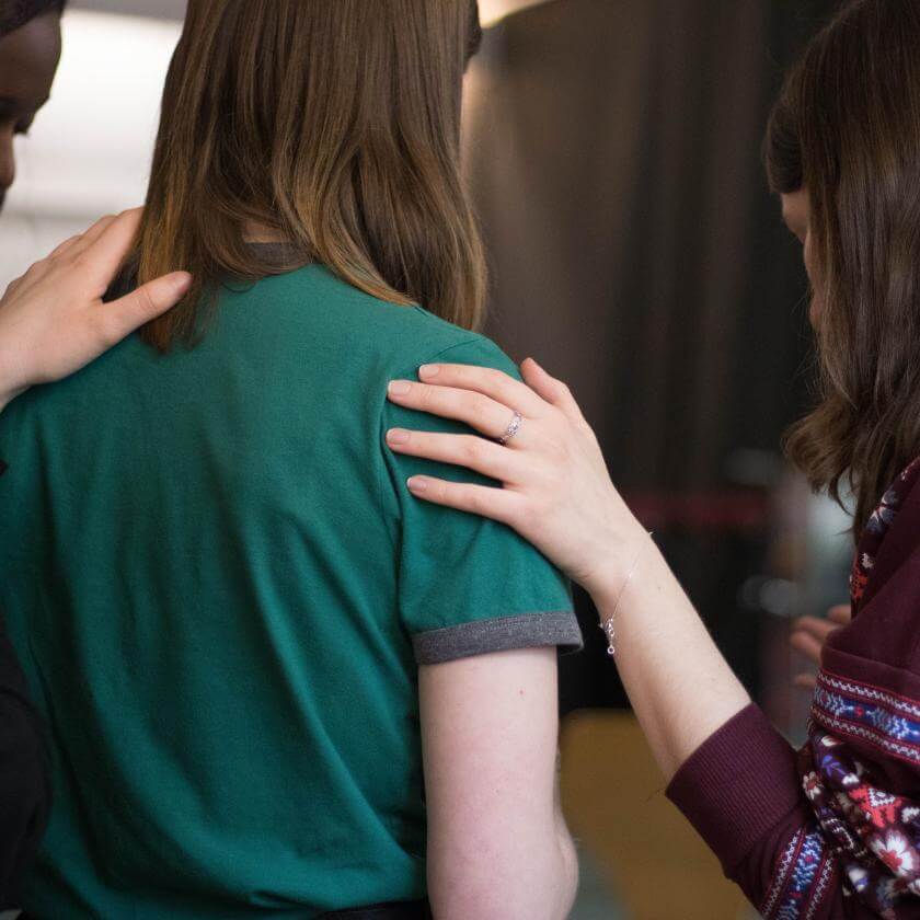 trois personnes debout l'une à côté de l'autre qui ont leurs mains sur les épaules des autres