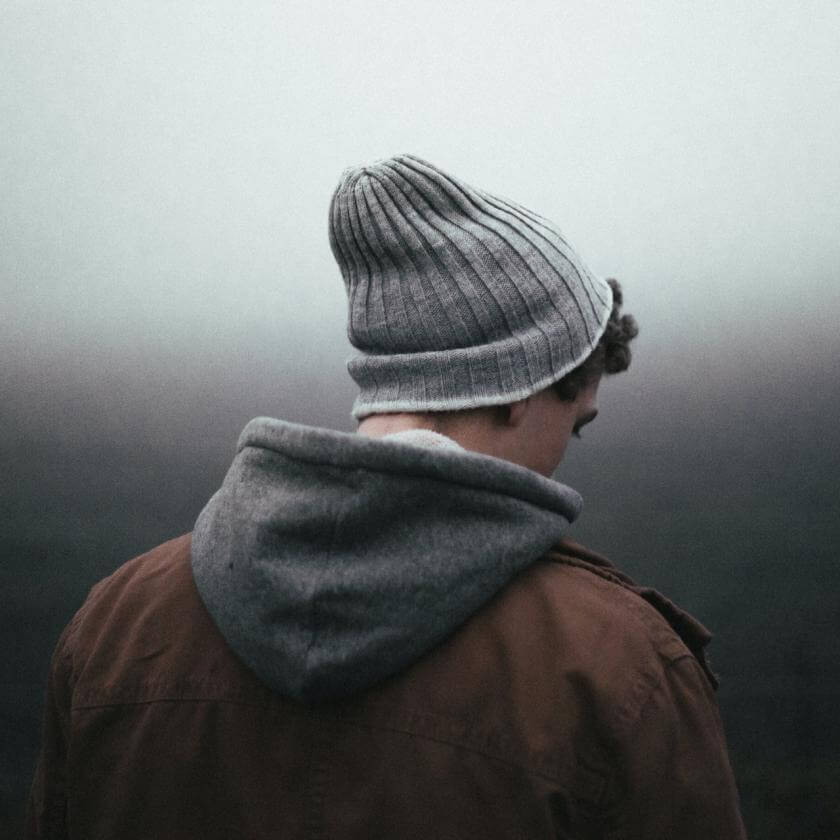 Person with masculine appearance from the back, staring at the ground
