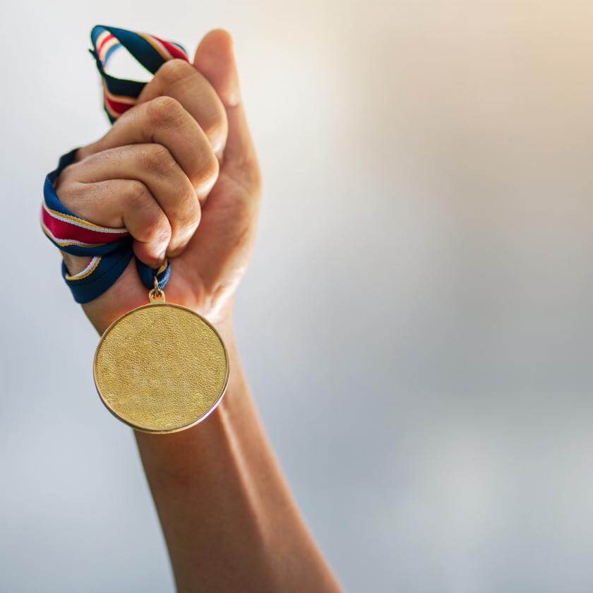 Raised hand holding a gold medal 