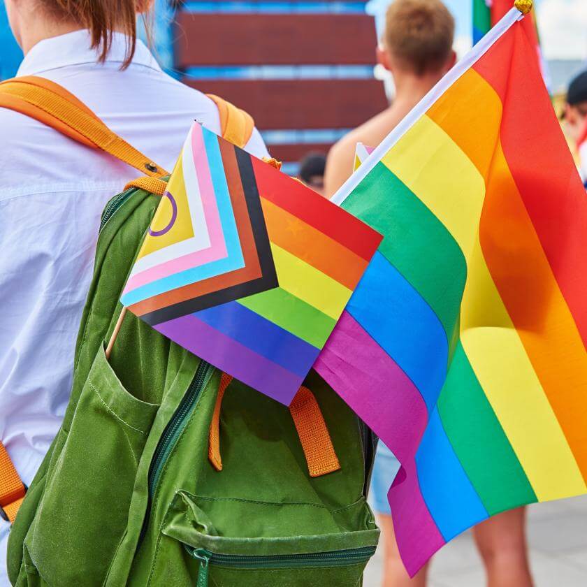 Person with a backpack and diverse  LGBTQIA2S+ flags