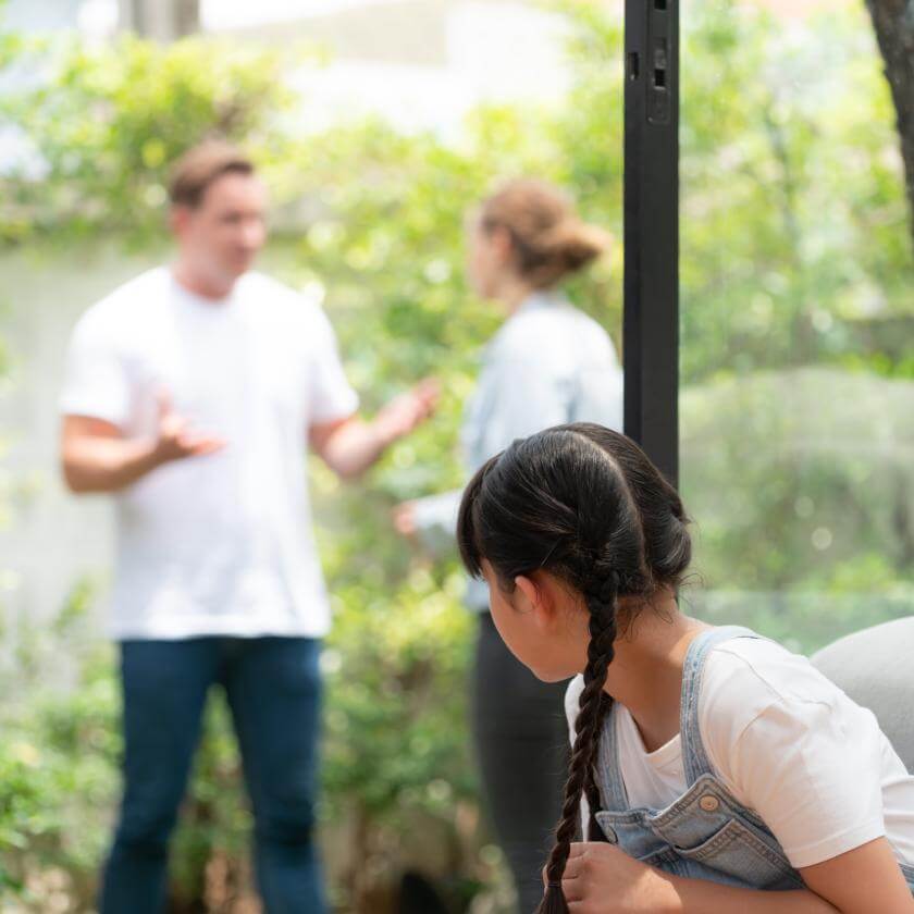 Child watching their parents arguing in the background