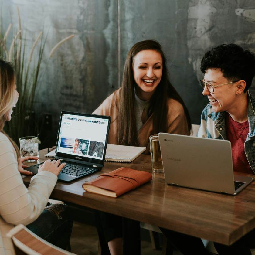 Group of friends sitting at a table and using their computers