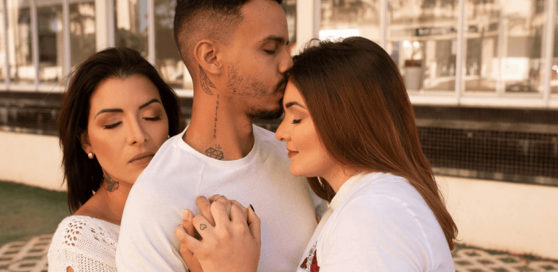 Trouple composé d'un homme et deux femmes qui s'enlacent