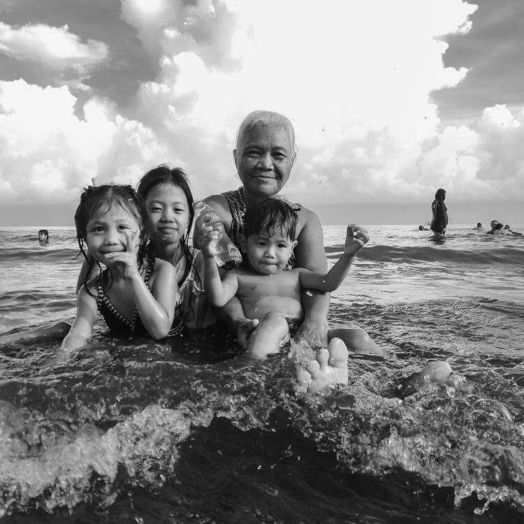 Adult woman and three children bathing in the sea