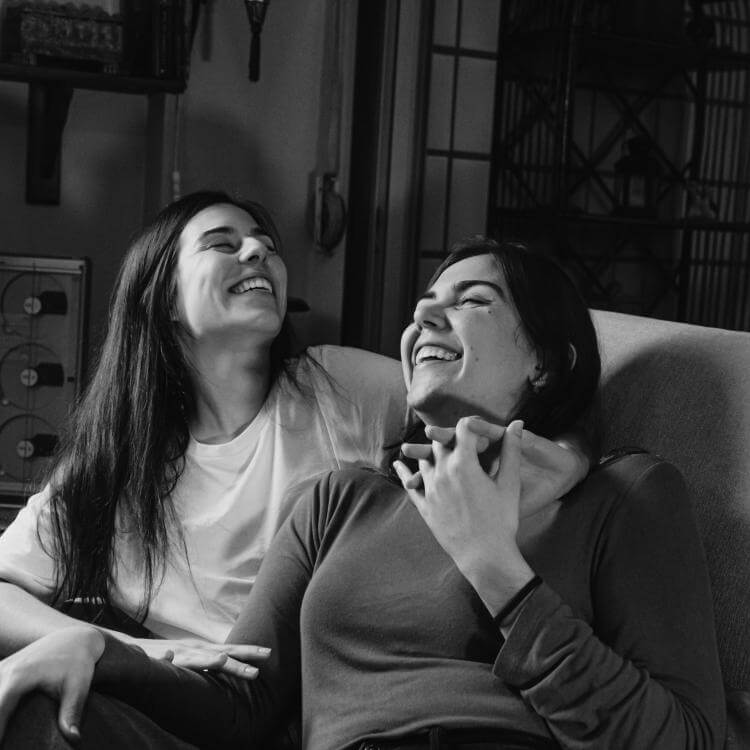 Deux femmes souriantes assises sur un divan